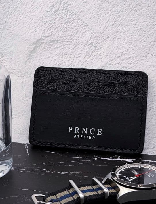A saddle-stitched card holder, photographed beside a watch